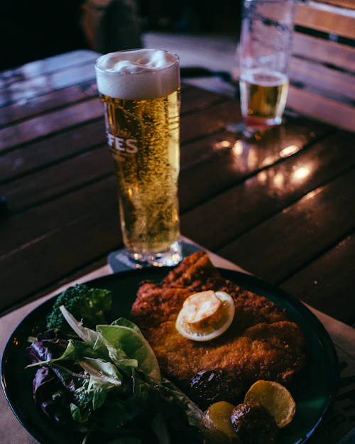 Schnitzel und ein Glas Bier auf einem Holztisch (Symbolbild)
